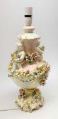 An Italian Capodimonte style lamp base, of pedestal urn form with applied putti and encrusted flower