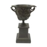 A bronze twin handled urn, cast with acanthus leaves and buds, raised upon a marble plinth with step