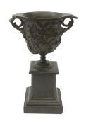 A bronze twin handled urn, cast with acanthus leaves and buds, raised upon a marble plinth with step