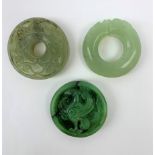 Two jadeite bi discs, largest D5.5cm, together with a nephrite jade disc with carved zoomorphic deta