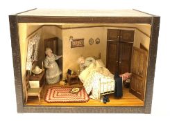 A 1/12th scale diorama of a cottage bedroom, depicting an elderly couple, he in bed, her by the door