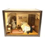 A 1/12th scale diorama of a cottage bedroom, depicting an elderly couple, he in bed, her by the door
