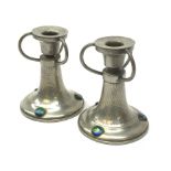 A pair of German pewter candlesticks, the circular bases with applied cabouchons, leading to a plann