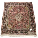 Persian pale red ground rug, the field decorated with flower heads, repeating guarded border, 117cm