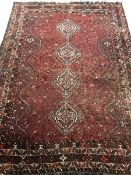 Large Persian red ground rug/carpet, the field decorated with multiple stylised motifs and quadruple