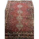 Large Persian red ground rug/carpet, the field decorated with multiple stylised motifs and quadruple