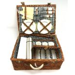 A wicker picnic hamper with accompanying contents.