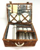 A wicker picnic hamper with accompanying contents.