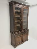 Late Victorian stained pine bookcase on cupboard, projecting on cornice, two glazed doors enclosing