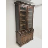 Late Victorian stained pine bookcase on cupboard, projecting on cornice, two glazed doors enclosing