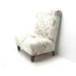Wide seat nursing chair upholstered in an ivory ground fabric with floral pattern, turned supports,