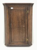 Late 19th century oak corner cupboard, projecting dentil cornice, enclosed by single panelled door,