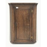 Late 19th century oak corner cupboard, projecting dentil cornice, enclosed by single panelled door,