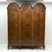 20th century walnut triple wardrobe, triple stepped arch top, enclosed by three figured doors, the i