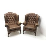 Pair Queen Anne style wingback armchairs upholstered in a deep buttoned studded tan leather