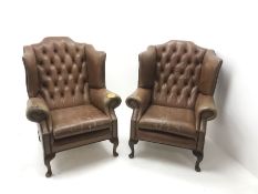 Pair Queen Anne style wingback armchairs upholstered in a deep buttoned studded tan leather