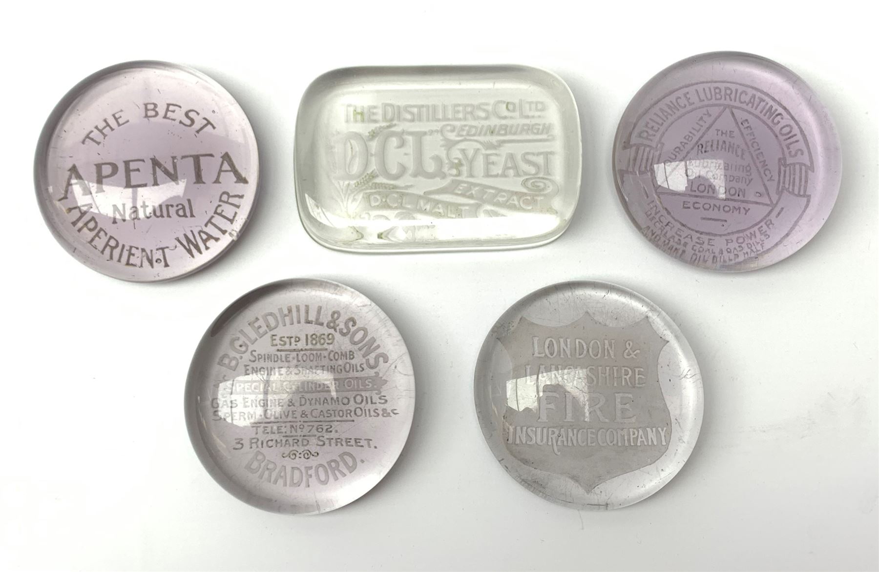 Five early 20th century promotional glass paperweights