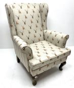 Wingback armchair upholstered in a grey fabric decorated with stags