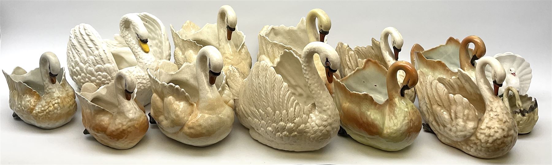 A large quantity of assorted sized ceramic planters modelled as swans.