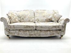 Three seat sofa upholstered in a pale gold ground fabric with floral pattern