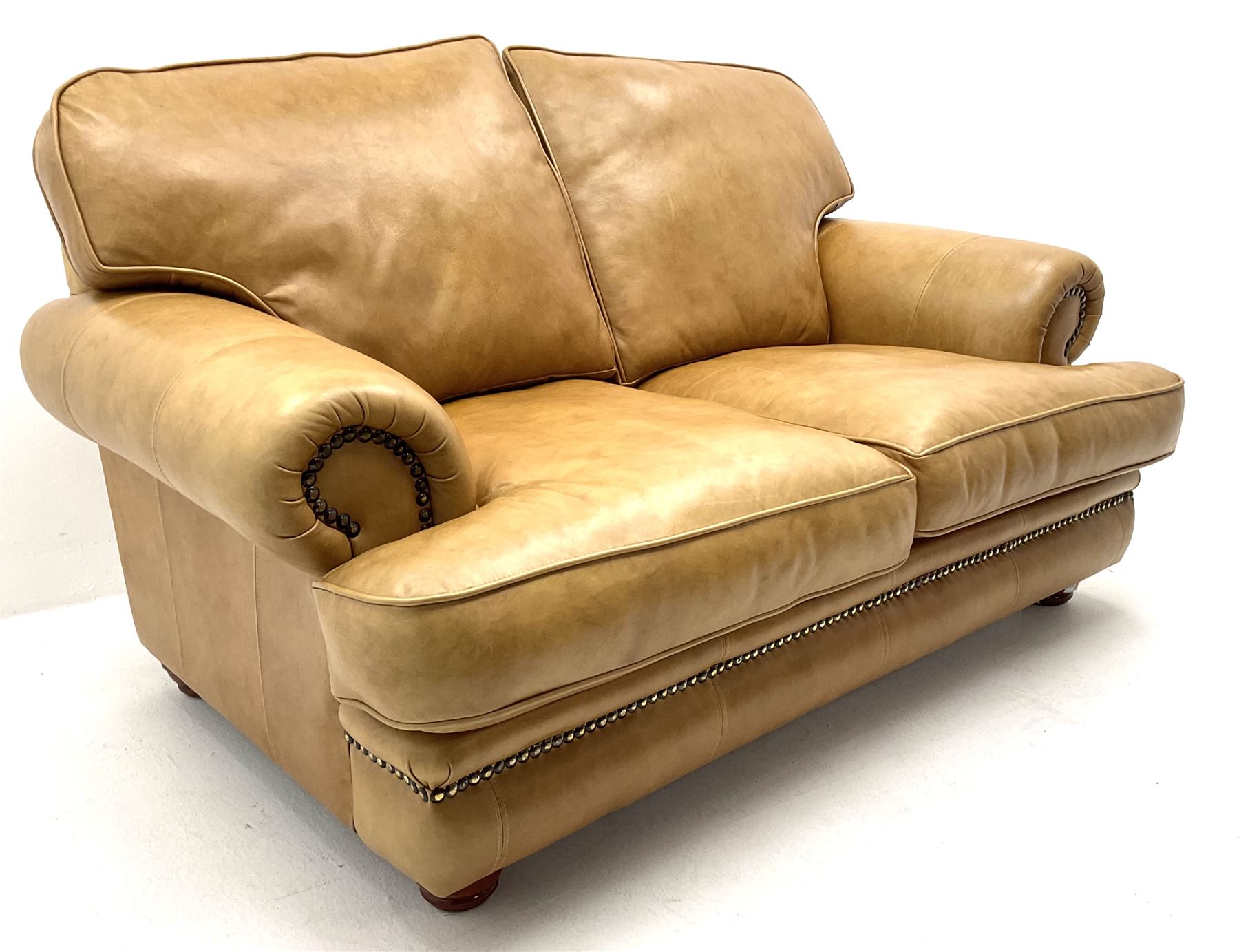 Two seat sofa upholstered in a studded tan leather