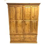 Pine wardrobe enclosed by two panelled doors and fitted with four long drawers