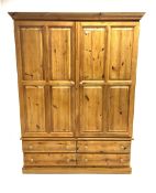 Pine wardrobe enclosed by two panelled doors and fitted with four long drawers