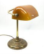 A brassed bankers lamp with spreading circular base and yellow glass shade