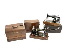 A group of five cased Singer sewing machines.