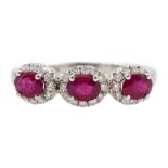 White gold three stone oval ruby and round brilliant cut diamond cluster ring