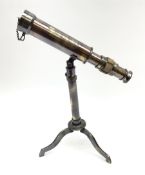 A small brass telescope mounted on an extending tripod base with folding feet