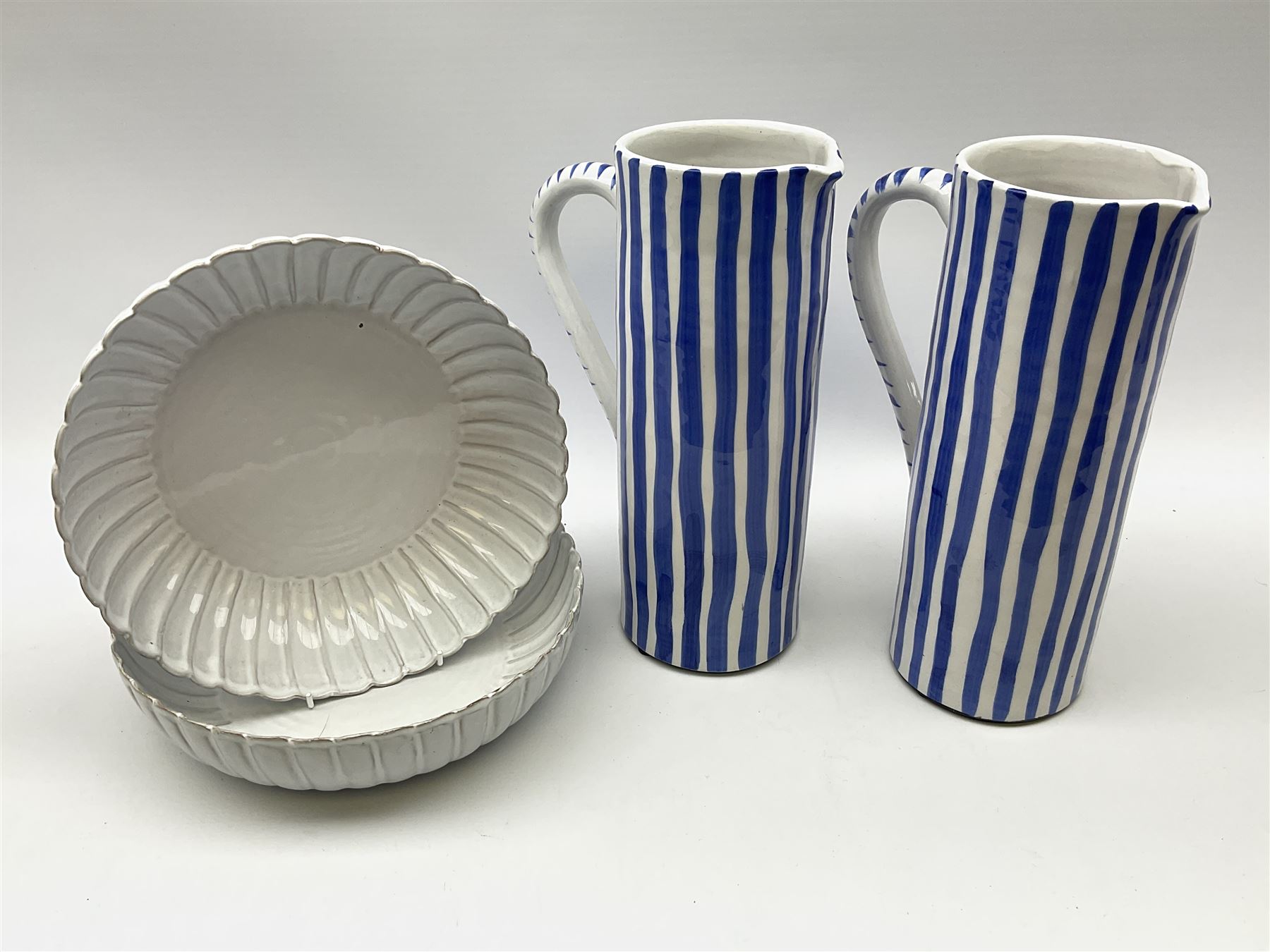 A pair of large pottery jugs with decorated with blue vertical stripes upon a white ground