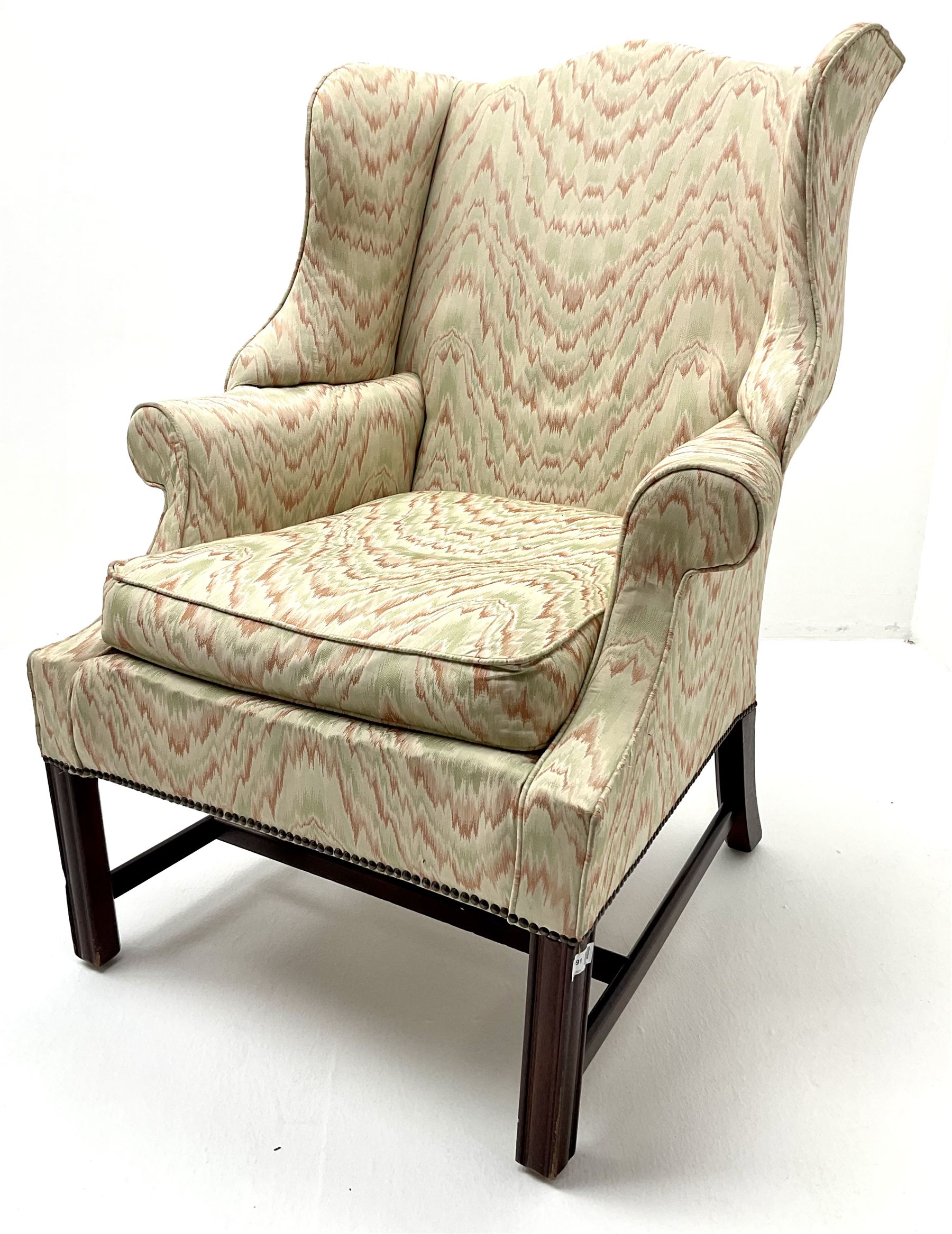 Georgian style mahogany framed wingback armchair upholstered in a beige ground fabric