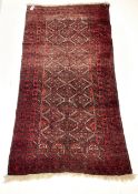 Persian red ground rug with repeating lozenge design