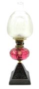 A Victorian oil lamp with cranberry glass facet cut honeycomb effect reservoir
