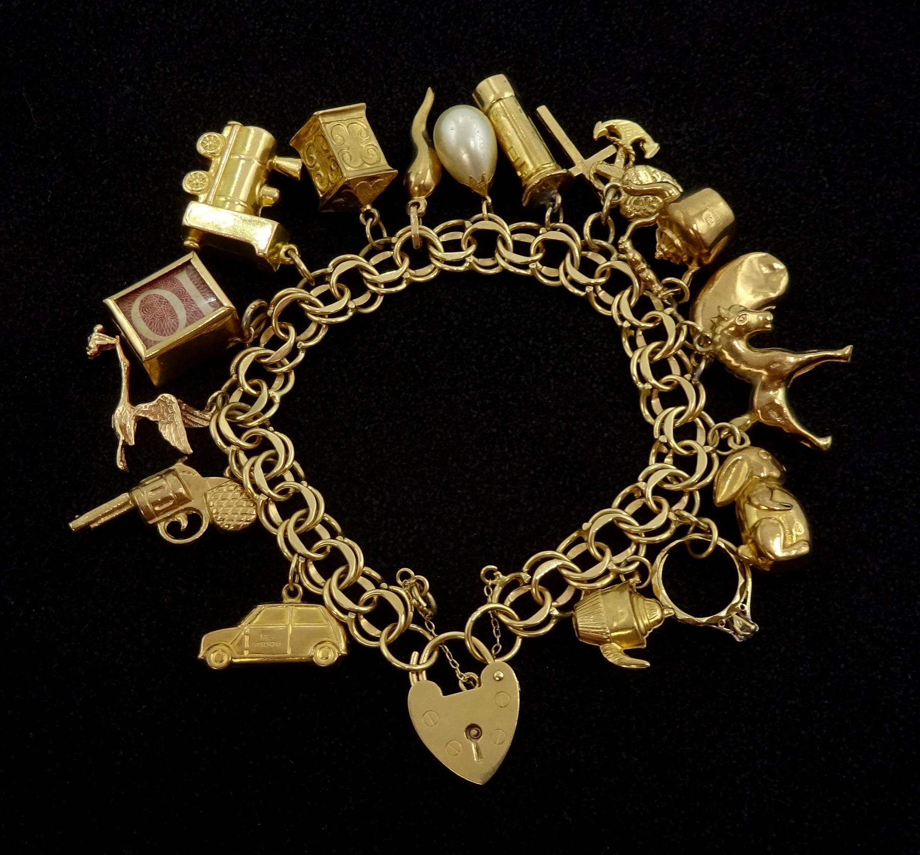 Gold link bracelet with heart locket and fifteen 9ct gold charms including train