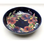 A large Moorcroft bowl decorated in the Iris pattern upon a dark blue ground