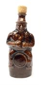 A treacle glazed stoneware bottle modelled as a man seated upon a barrel