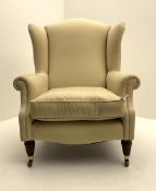 Late 20th century traditional shaped wingback armchair upholstered in pale fabric