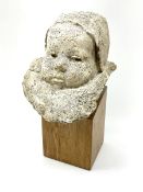 Composite stone bust depicting a baby with ruffle on a oak plinth