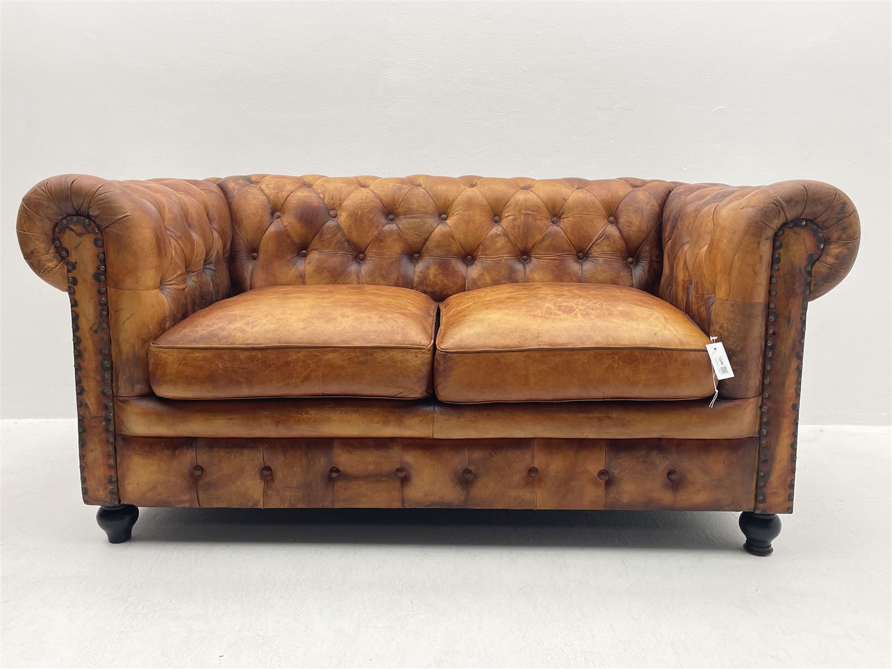 Two seat Chesterfield sofa upholstered in antique finish tan buttoned leather