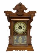 An early 20th century spring driven alarm clock in the style of an American �gingerbread� shelf clo
