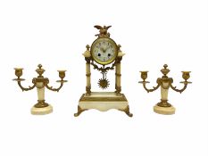 A late 19th century French portico clock with a pair of matching double light candelabra