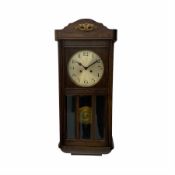 A 1930�s oak cased wall clock with an eight-day going barrel movement striking the hours and half ho