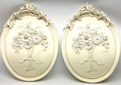 Pair of ceramic wall plaques each decorated in relief with scroll detail and ribbon-tied flowers