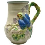 Clarice Cliff baluster jug moulded with a blue budgerigar perched upon branch with green rustic hand