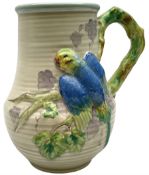 Clarice Cliff baluster jug moulded with a blue budgerigar perched upon branch with green rustic hand