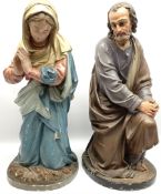 Two religious painted plaster figures of Mary and Joseph kneeling on oval plinths