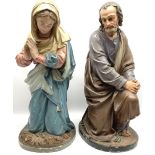 Two religious painted plaster figures of Mary and Joseph kneeling on oval plinths