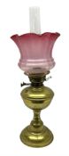 Brass oil lamp with foliate etched cranberry glass shade